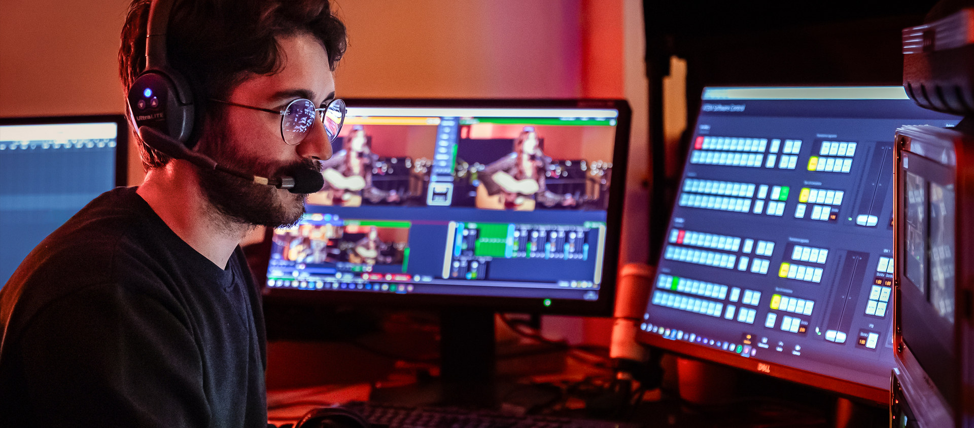 Tecnico di regia con cuffia davanti ai monitor di anteprima durante una diretta